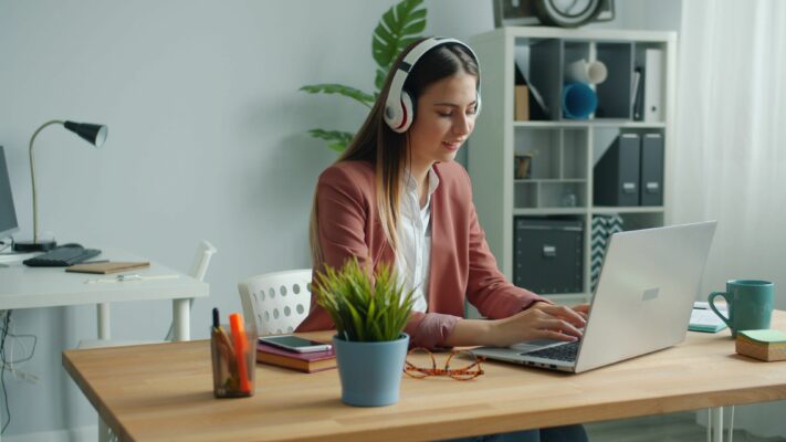 Persona concentrada trabajando en un escritorio ordenado con auriculares para cuidar su salud mental laboral